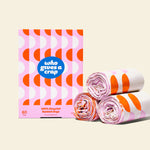 Three rolls and a box of Who Gives a Crap small recycled garbage bags with pink and orange packaging