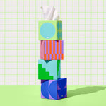 Four Who Gives a Crap tissue boxes stacked on top of each other against green and white bathroom wall