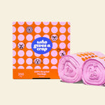 Two rolls and a box of Who Gives a Crap recycled dog poo bags with pink and orange packaging