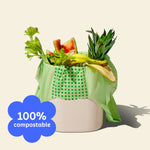 Who Gives a Crap compostable rubbish bag sits in compost bin with food scraps spilling out the top