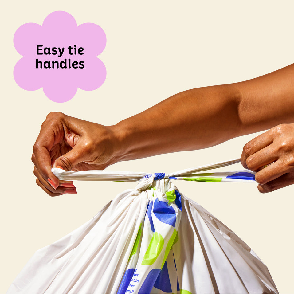 Two hands ties close Who Gives a Crap large recycled garbage bag with the easy tie handles.