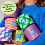 Woman holds handful of colourful Who Gives a Crap recycled toilet paper rolls
