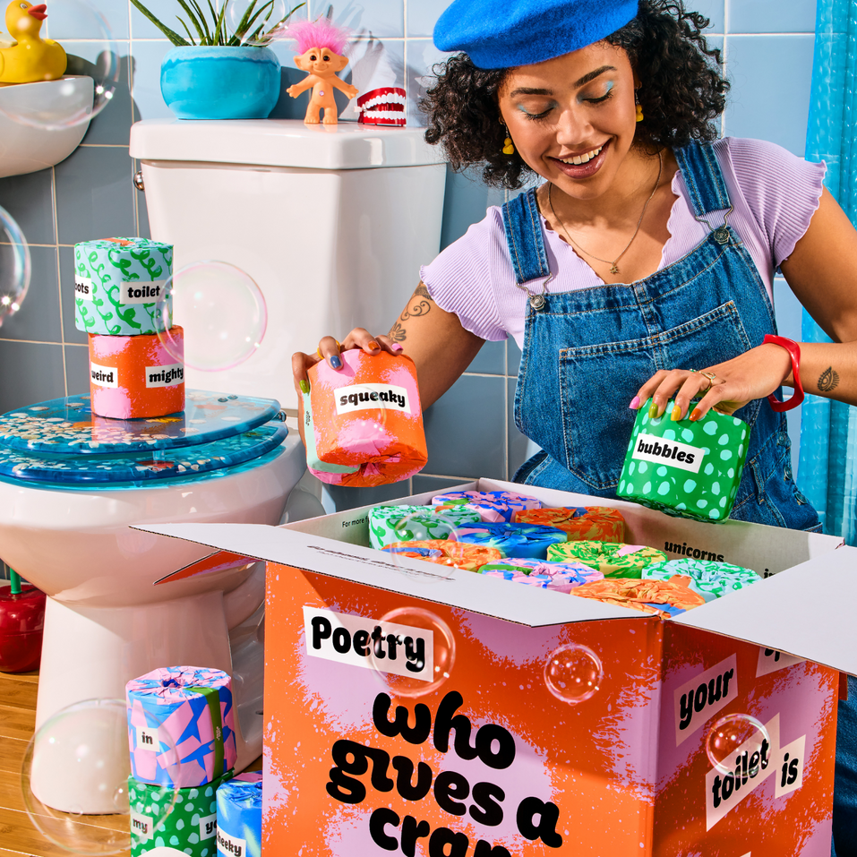 A person unboxing Poetry Edition, a box of 48 eco-friendly toilet paper rolls with colourful wrappers that feature words used to write poems.