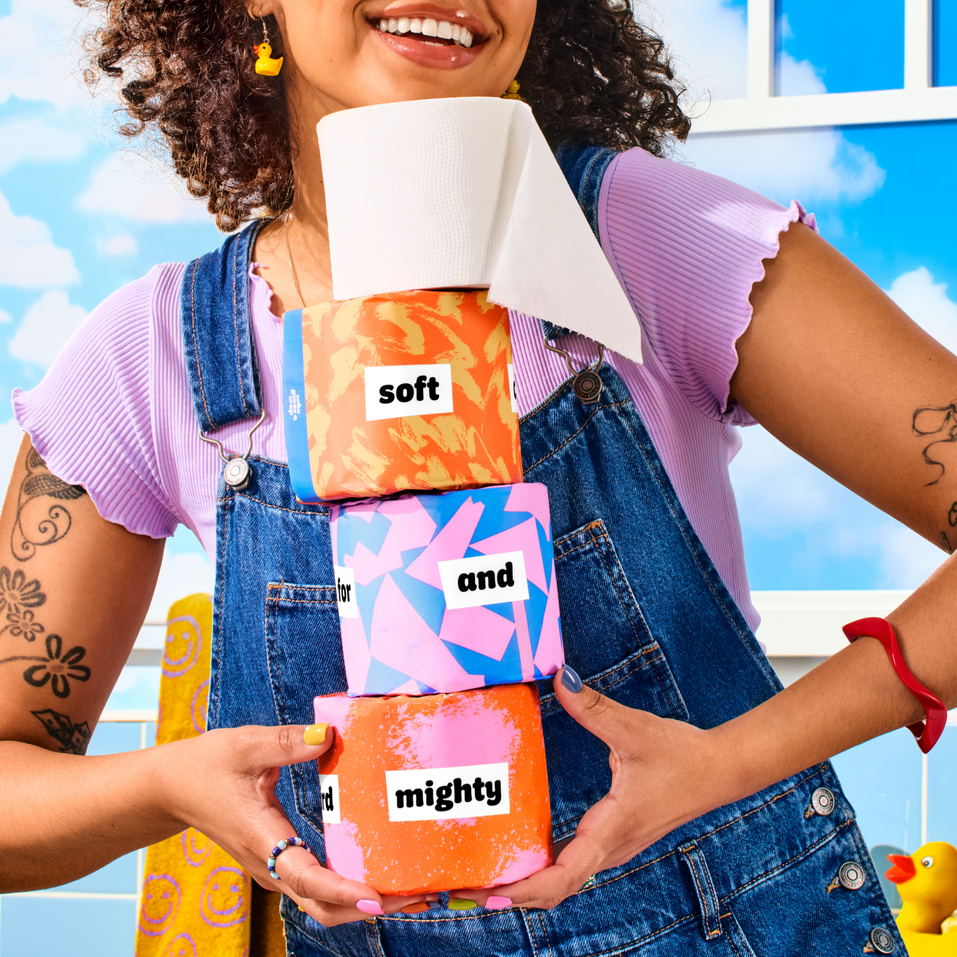 Person holding stacked toilet paper rolls labeled 