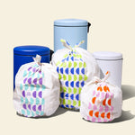 Three full garbage bags with patterned designs, displayed next to trash cans of varying sizes, highlighting the different bag sizes.