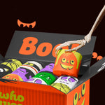 Open Spooky Edition box of toilet paper with skeleton hand lifting pumpkin-themed roll, surrounded by colourful monster wrappers.