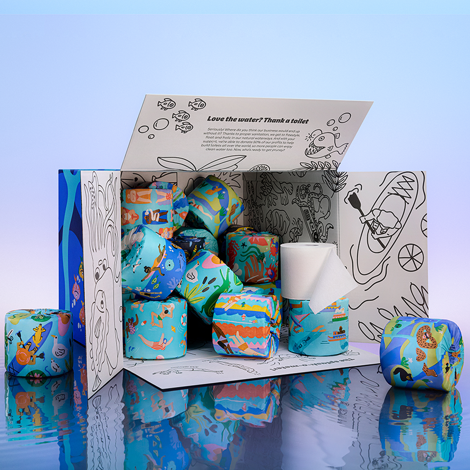An open Who Gives A Crap Splash Edition box filled with colourfully illustrated bamboo toilet rolls, with the inside lid reading 