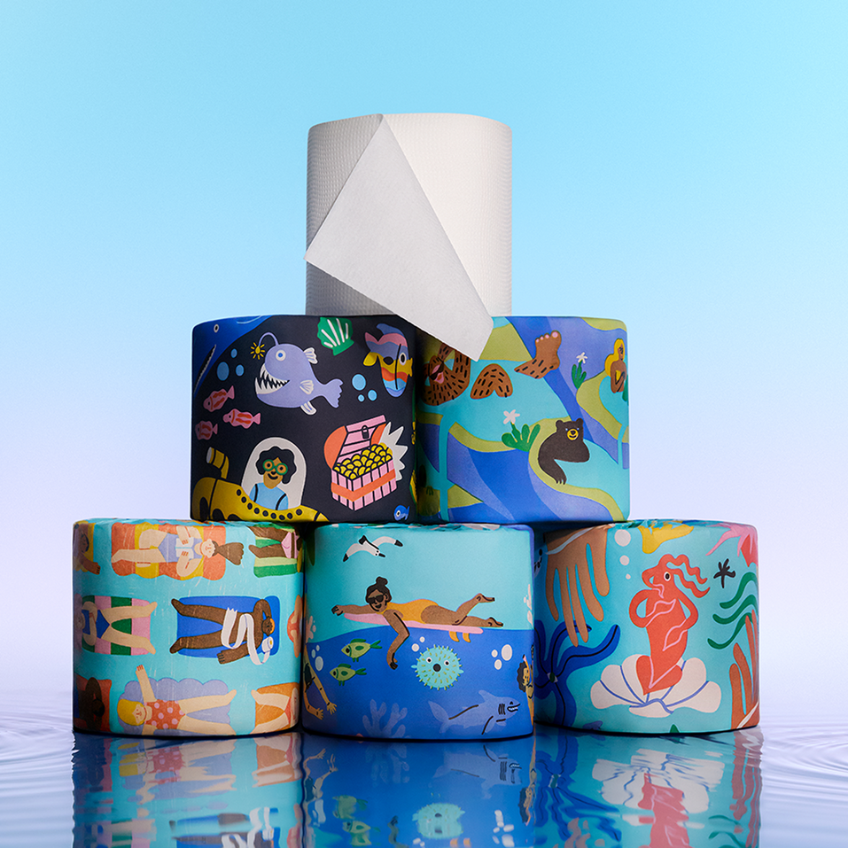 A pyramid stack of Who Gives A Crap Splash Edition bamboo toilet rolls featuring ocean and water-themed illustrations including mermaids, sea creatures and swimmers