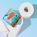A Who Gives A Crap Splash Edition roll featuring a bold red mermaid illustration resting against an unwrapped white bamboo toilet paper roll