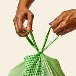 Hands tying a compostable food scrap bag, demonstrating its ease of use for quick and secure closure.