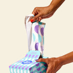 Hand pulling a trash bag from the box, showcasing easy dispensing and quick access.