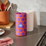 A purple and orange wrapped roll of kitchen towel roll sits next to an unwrapped roll on a kitchen counter.