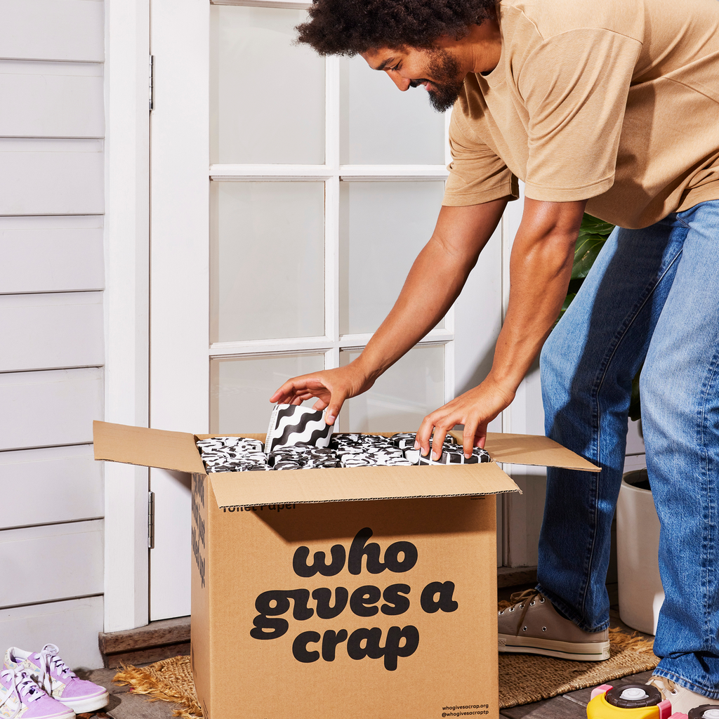 Man collecting box of Who Gives a Crap toilet paper from front porch of home