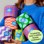 Woman holds handful of colourful Who Gives a Crap recycled toilet paper rolls