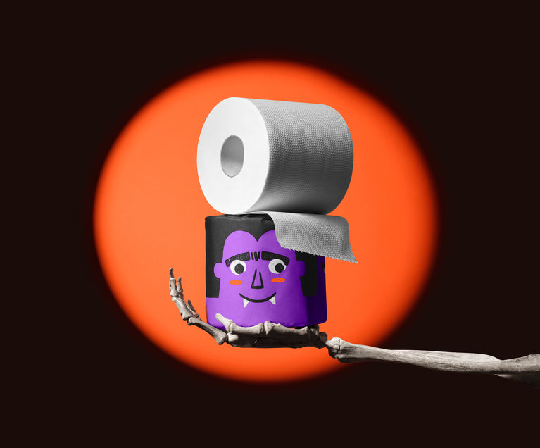 Skeleton hand holding a purple vampire roll of Spooky Edition bamboo toilet paper, unravelling in an orange spotlight