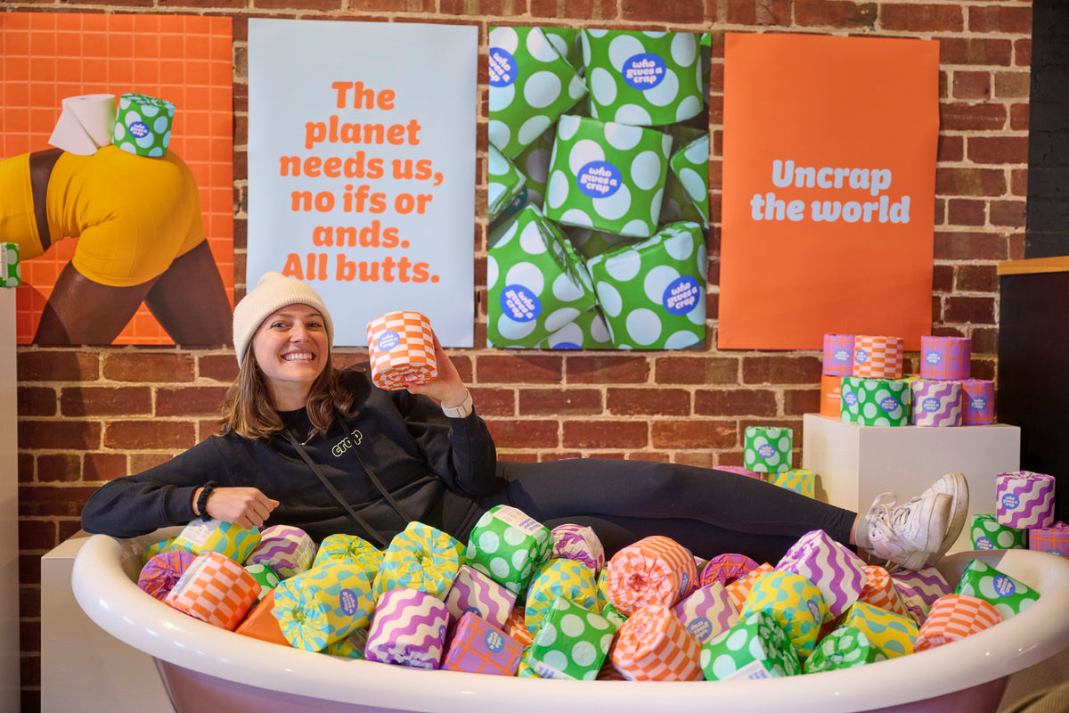 Who Gives a Crap smiling employee lies in bathtub filled with recycled toilet paper in colourful packaging