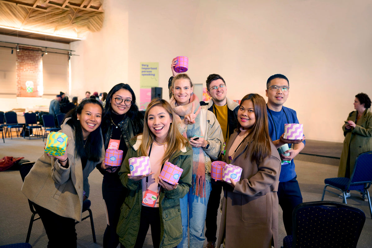 Who Gives a Crap employees smiling holding recycled toilet paper in colourful packaging
