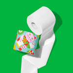Close-up of an unrolled white roll of 3-ply bamboo toilet paper beside a roll in a festive wrapper, on a green background.