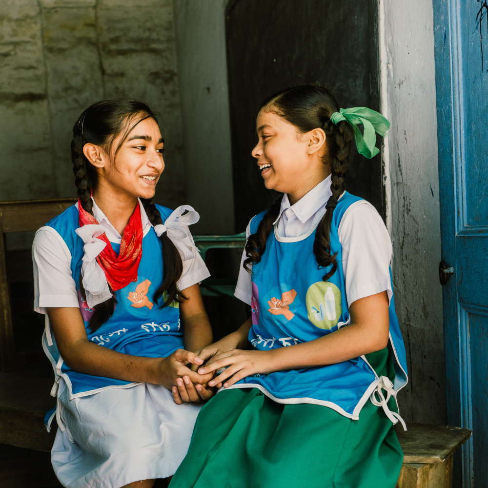 Two girls smiling at each other holding hands