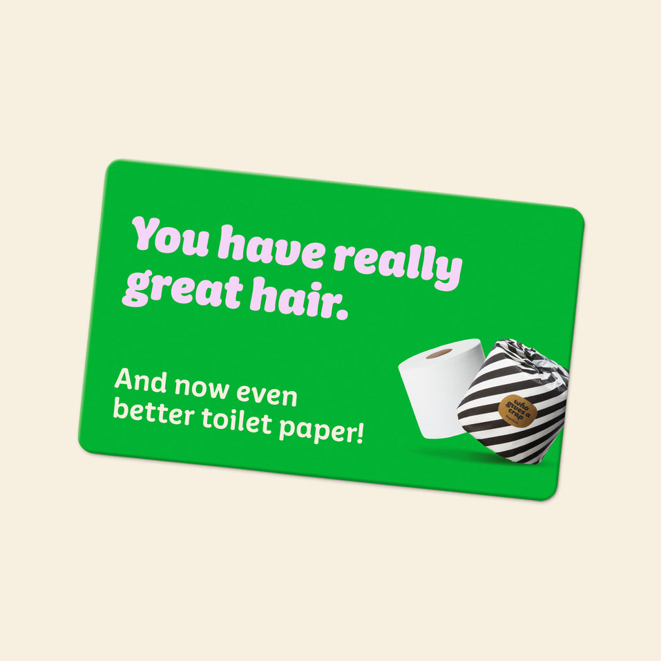 A gift card with the line of text “You have really great hair.” followed by the line of text “And now even better toilet paper!” written on it.